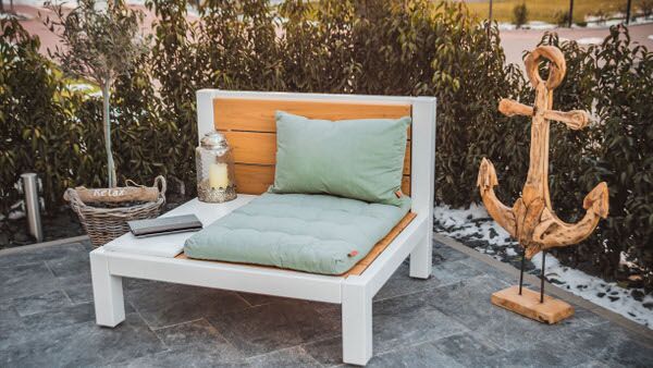 Gartenmöbel modern und aus Massivholz. Eine Holzlounge für eine Person mit Kissen und Ablageplatte.